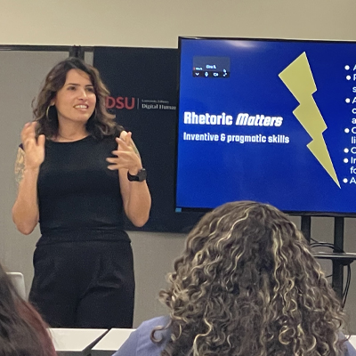 woman speaking to students, slide shoiws Rhetric Matters