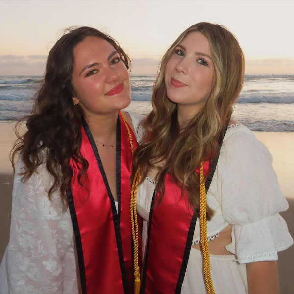 two woman with graduation sashes at beach