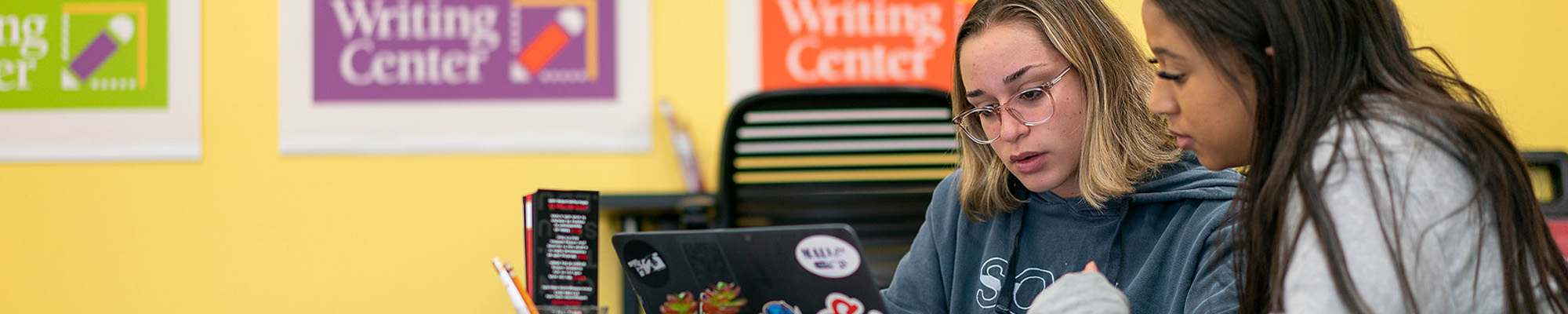 student and tutor in writing center looking at computer